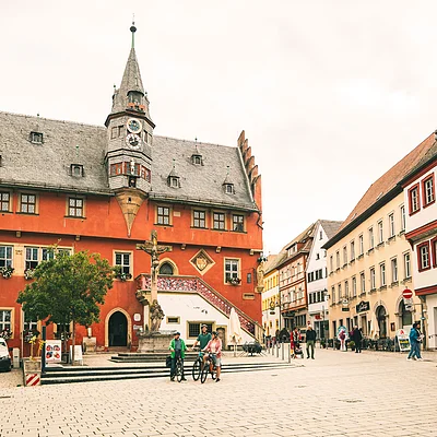 Historisches Rathaus mit Uhrturm und Menschen auf Fahrrädern auf gepflastertem Platz in Stadtzentrum